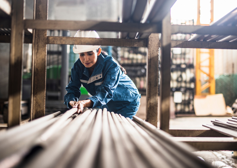 Person with safety gear on stacking steel in factory