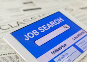 Job Search on laptop laying on newspaper classified ads