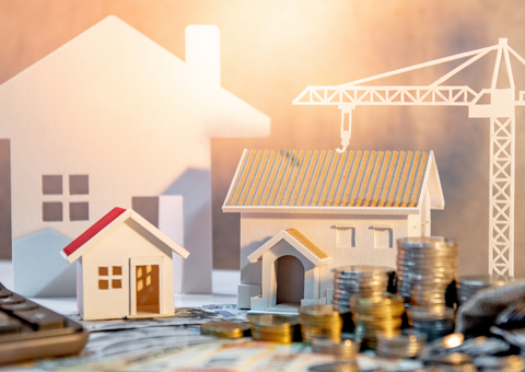 Fake houses and crane with stacks of coins